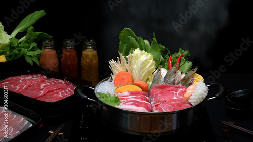 Принти на полотні Close-up view of shabu shabu in hot pot with black background, fresh sliced meat