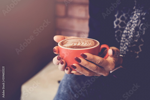 Woman hands holding red cup of coffee latte, relaxing, thinking, business meeting concept