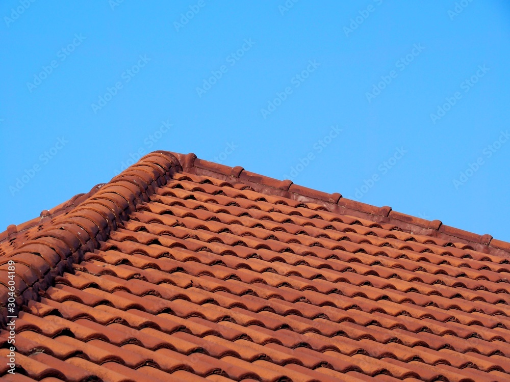 Roof covered with orange wavy tiles with blue sky background. Roof covered with orange wavy tiles with blue sky background.