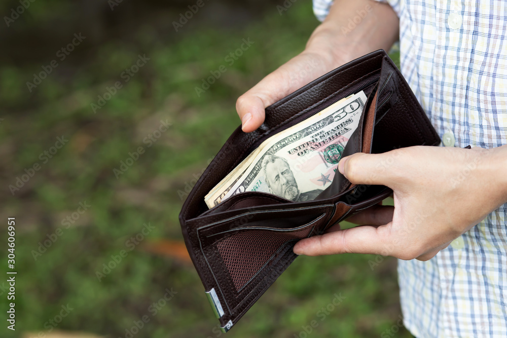 Businessman Person holding an wallet in the hands of an man take money out  of pocket. Photos | Adobe Stock