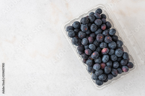 Fotografie, Tablou Open clamshell container of blueberries on a white granite counter