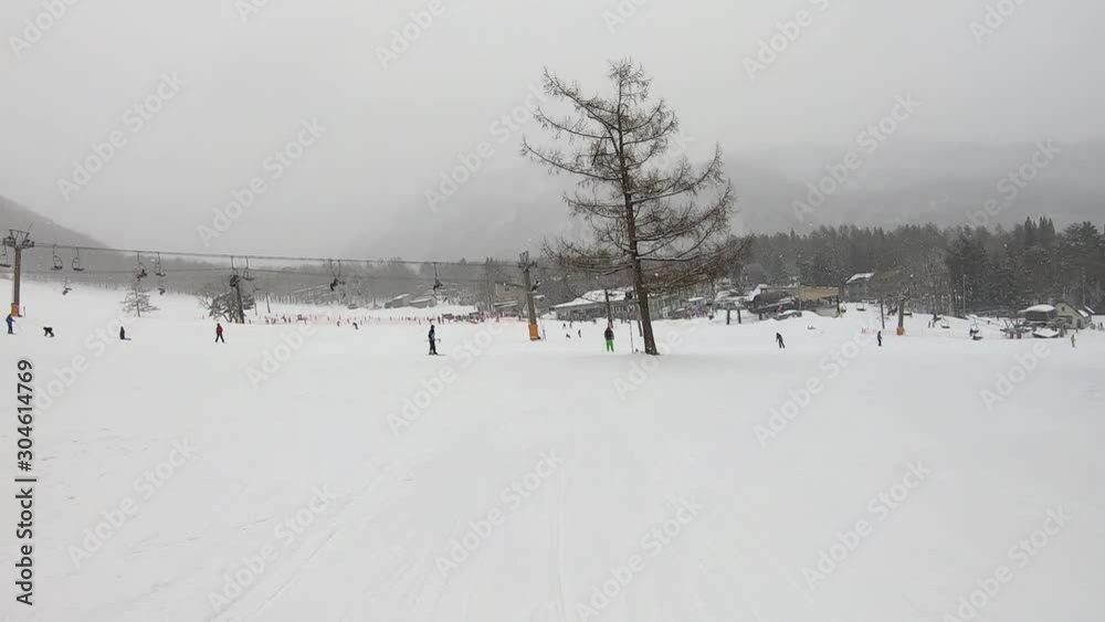 Following A Person Skiing Down A Steep Mountain Covered In Powder Snow With Other People And A Chair Lift In The Distance Following A Person Skiing Down A Steep Mountain Covered In Powder Snow With Other People And A Chair Lift In The Distance