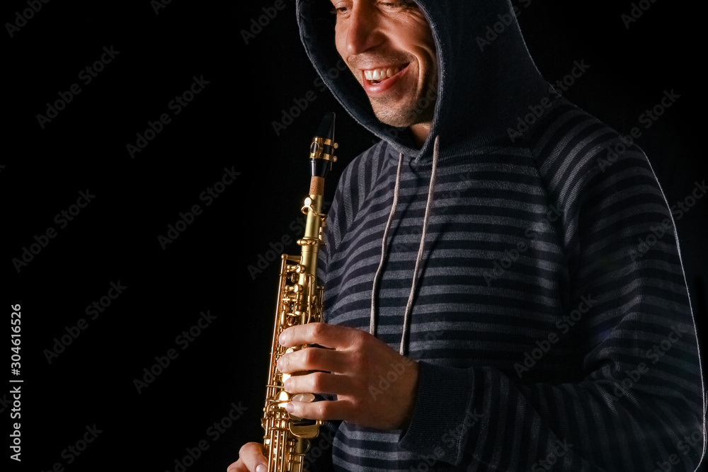 Naklejka premium soprano saxophone in the hands of a guy on a black background