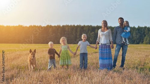 A large family is lined up and with a dog poses in front of the camera.