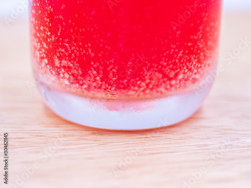 Closeup of a glass of cold multivitamin water dissolving from effervescent tablet pills sparkling fizzy bubbles on wooden table.