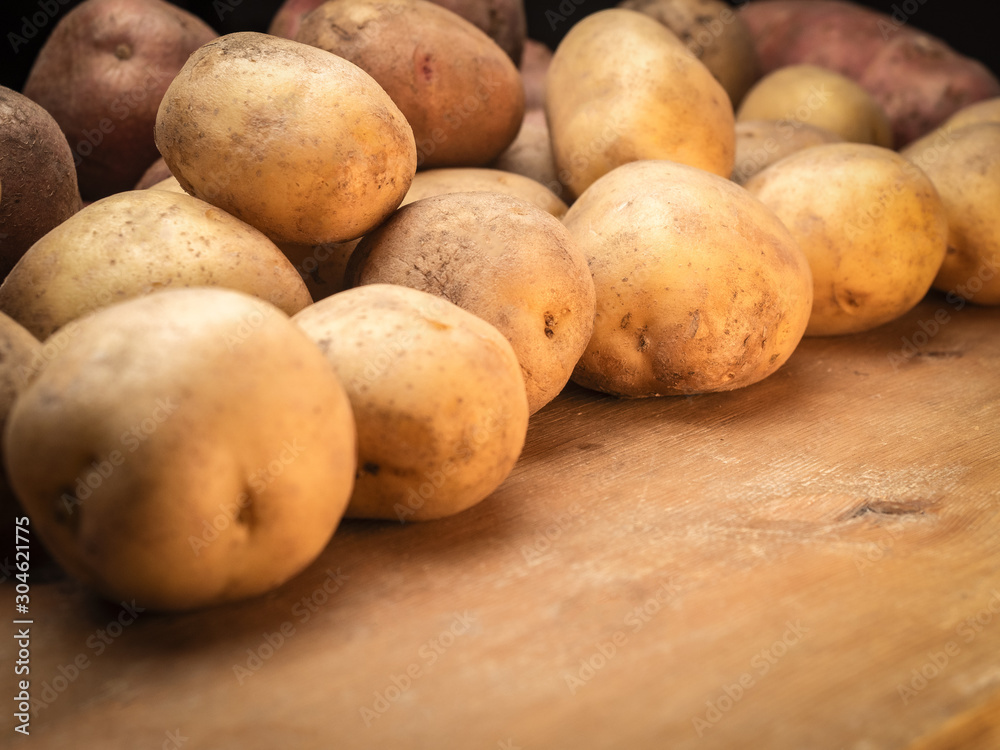 Rustic organic potatoes. Vegetables from farmhouse field is lying in bulk on wooden boards Rustic organic potatoes. Vegetables from farmhouse field is lying in bulk on wooden boards
