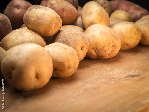 Rustic organic potatoes. Vegetables from farmhouse field is lying in bulk on wooden boards