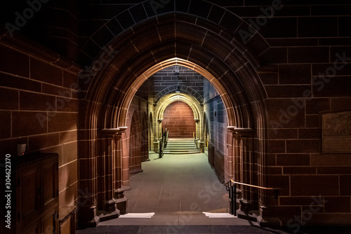Scary pointy arcade, made of stone bricks leading to a dead end corridor dimly lit. Concept mystery and danger.
