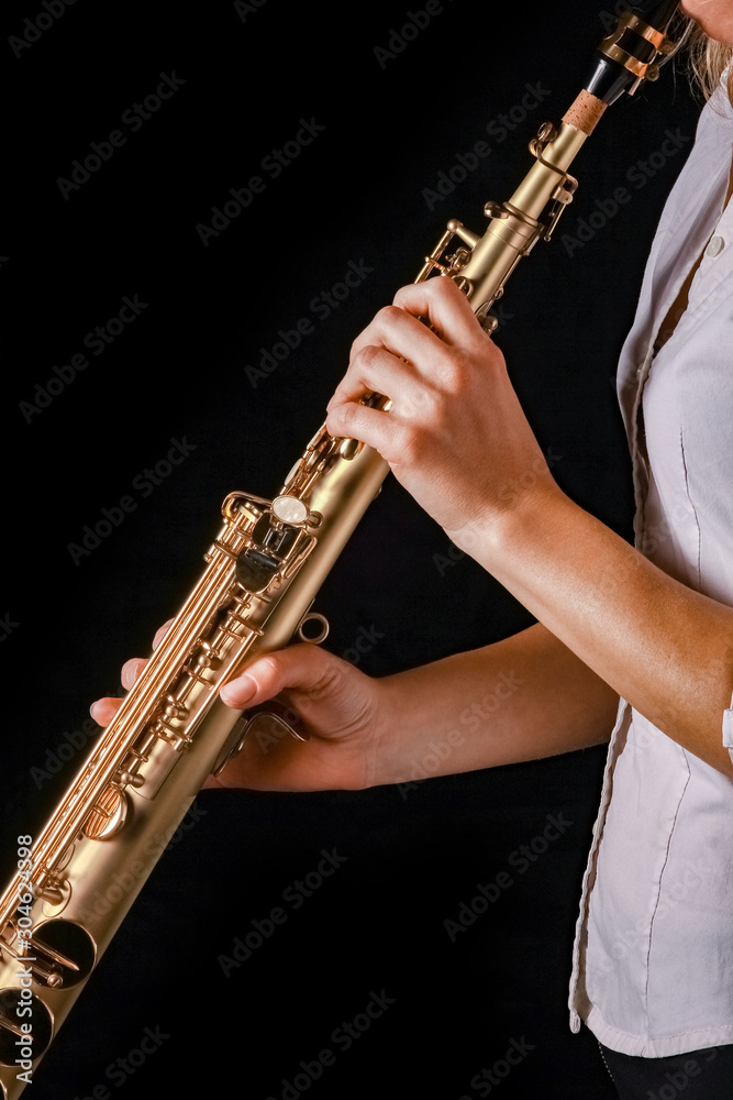 Fototapeta premium soprano saxophone in the hands of a girl on a black background