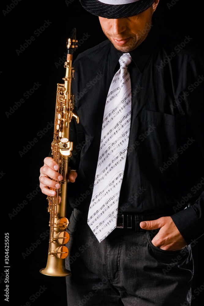 Naklejka premium soprano saxophone in the hands of a guy on a black background