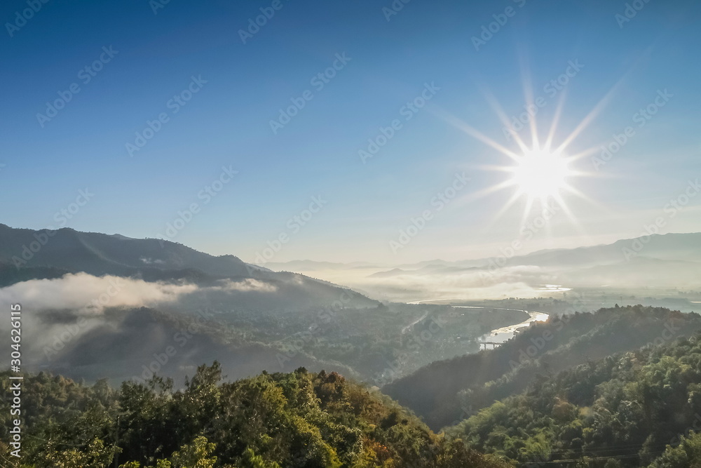Mountain view misty morning above Kok river and Tha Ton City in valley around with sea of mist and blue sky background, sunrise at Wat Tha Ton, Tha Ton District, Fang, Chiang Mai, northern Thailand.