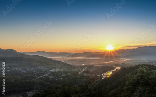 Mountain view misty morning above Kok river and Tha Ton City around with sea of mist and blue sky background, sunrise at Wat Tha Ton, Tha Ton District, Fang, Chiang Mai, northern of Thailand.