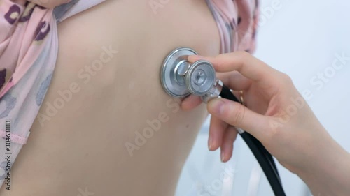 Doctor and patient on preventive examination. Pediatrician woman listening to heartbeat heart, lung function of child girl back using stethoscope in clinic, closeup view. Healthcare medicine concept.