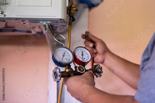 Air conditioning technicians check the air conditioners with a pressure gauge.