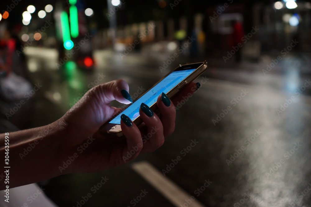 Mobile phone in female hands in the night city