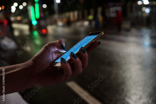 Obraz na płótnie Mobile phone in female hands in the night city w salonie