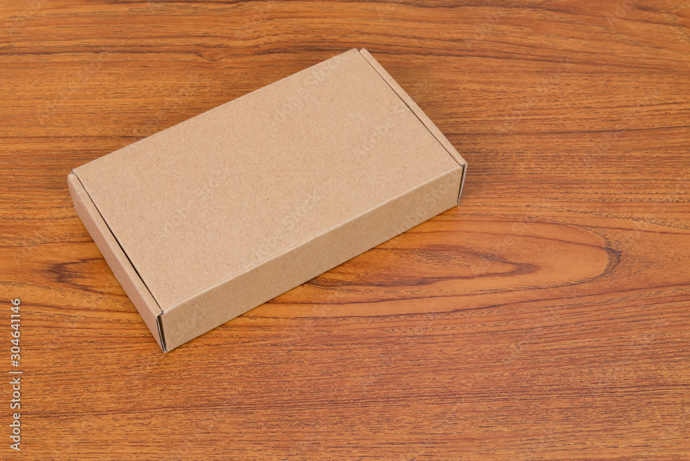 Empty brown cardboard box or tray for mock up on the wooden table with copy space. Empty brown cardboard box or tray for mock up on the wooden table with copy space.