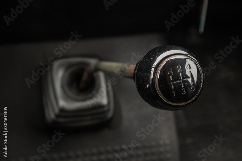 A gear stick of an old van. Visible knob, stick and rubber boot on the floor.