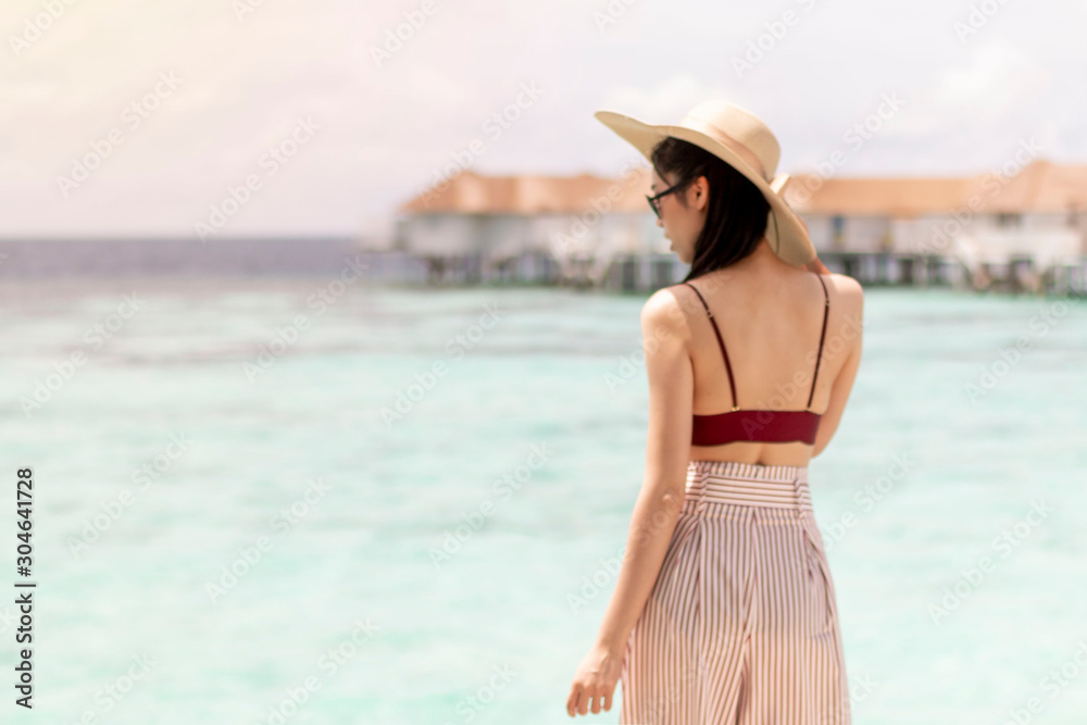 Blurred background. Summer vacation. Silhouette of a girl facing into the sea. Vintage style photo. Blurred image, girl turning her back to the camera, facing in to the sea.