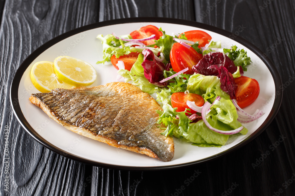 Baked dorado (sea bream) fillet served with fresh vegetable salad close-up on a plate. horizontal Baked dorado (sea bream) fillet served with fresh vegetable salad close-up on a plate. horizontal