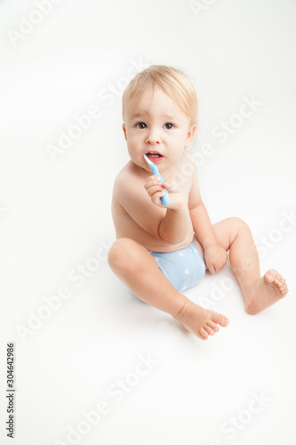 Little boy brushing his teeth on white background 