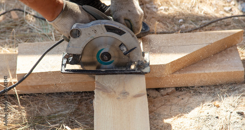 A worker cuts a wooden board at a construction site