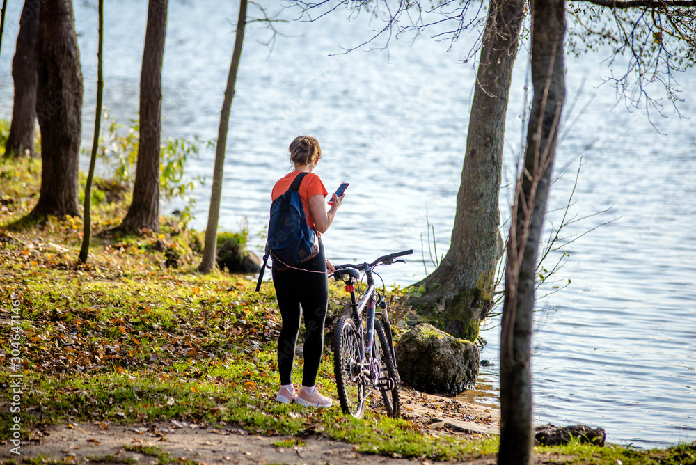 Girl with a Bicycle photographs the lake in the autumn Park Girl with a Bicycle photographs the lake in the autumn Park