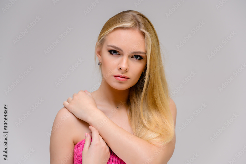 Beauty concept is a pretty model right in front of the camera. Close-up portrait of a beautiful blonde girl with excellent makeup with long smooth hair on a white background.