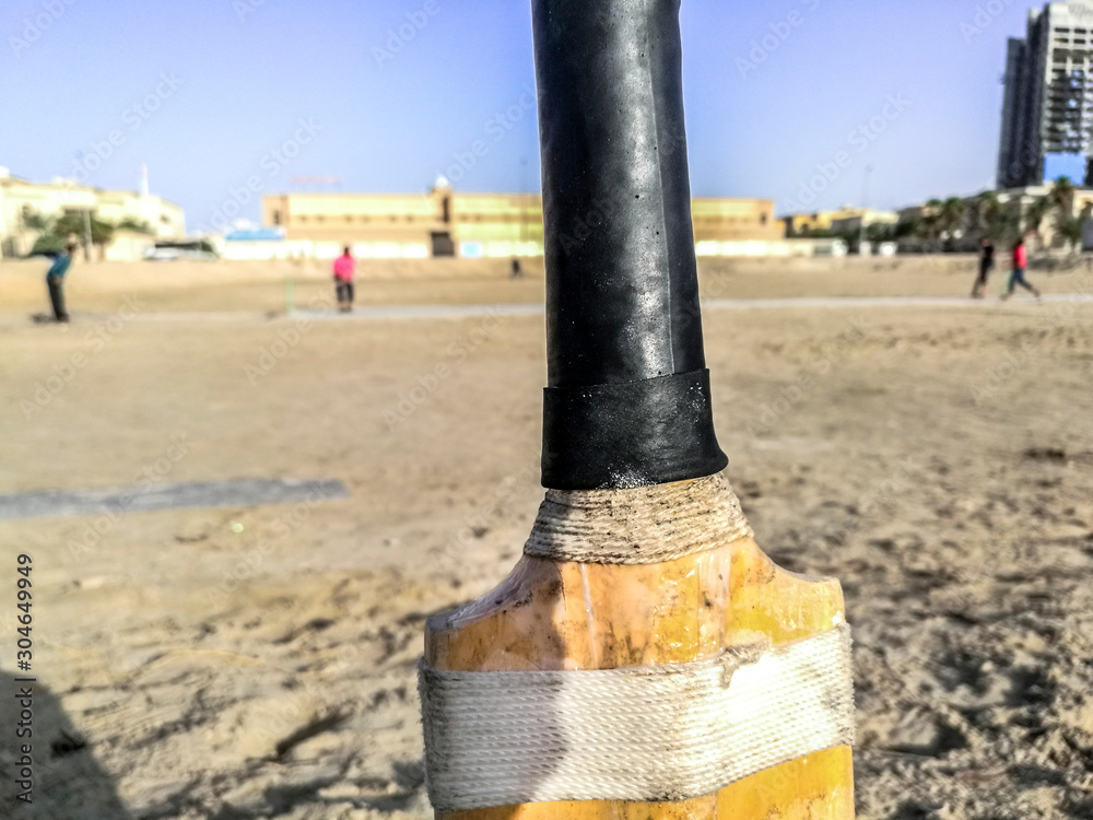 closeup of a cricket bat and players are playing in the background closeup of a cricket bat and players are playing in the background