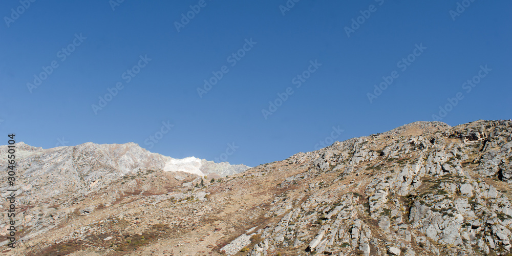 Mountain Landscape with Blue Sky. Copy Space above Mountains horizon over range of peaks valleys and cliffs. Natural floor of the earth. Panoramic canvas background design element. Leh Ladakh, India.