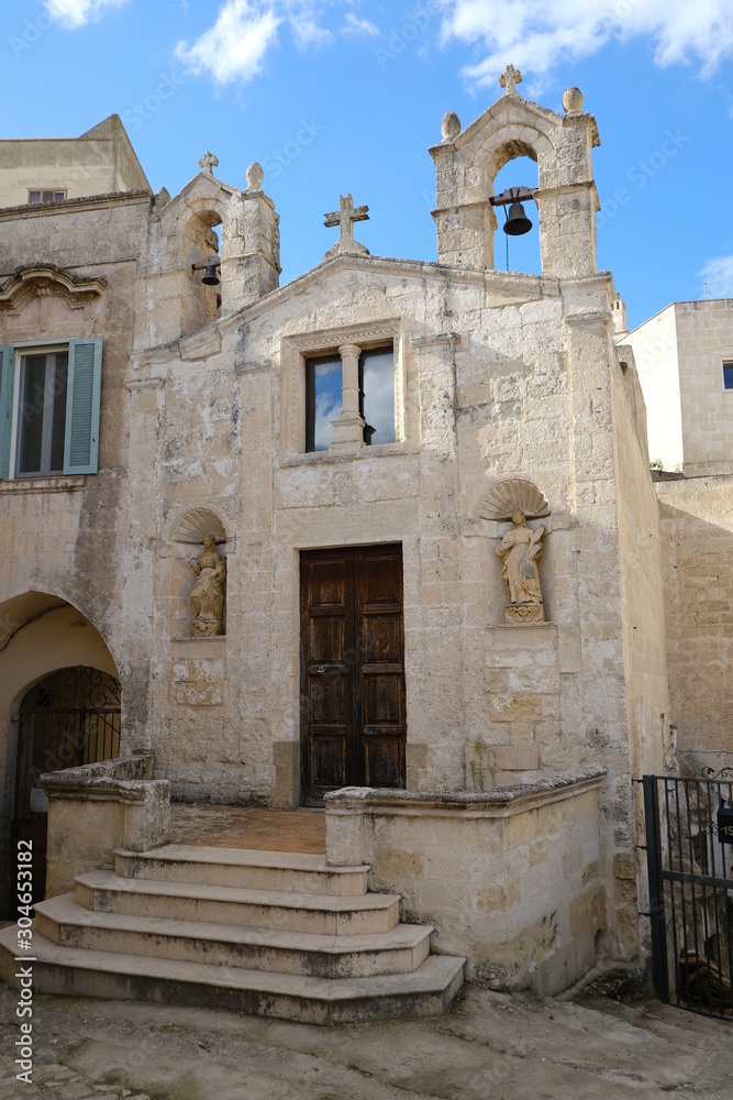 Church of San Biagio in Matera located in the Foggiali area. The construction is made of blocks of tufa stone of beige color. Facade with two small bells.