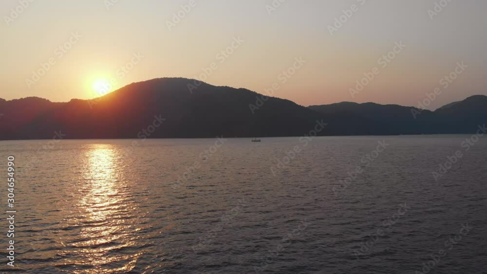 Yachting, a beautiful white yacht is sailing off the coast. Pink sunset the sun sets behind the mountains
