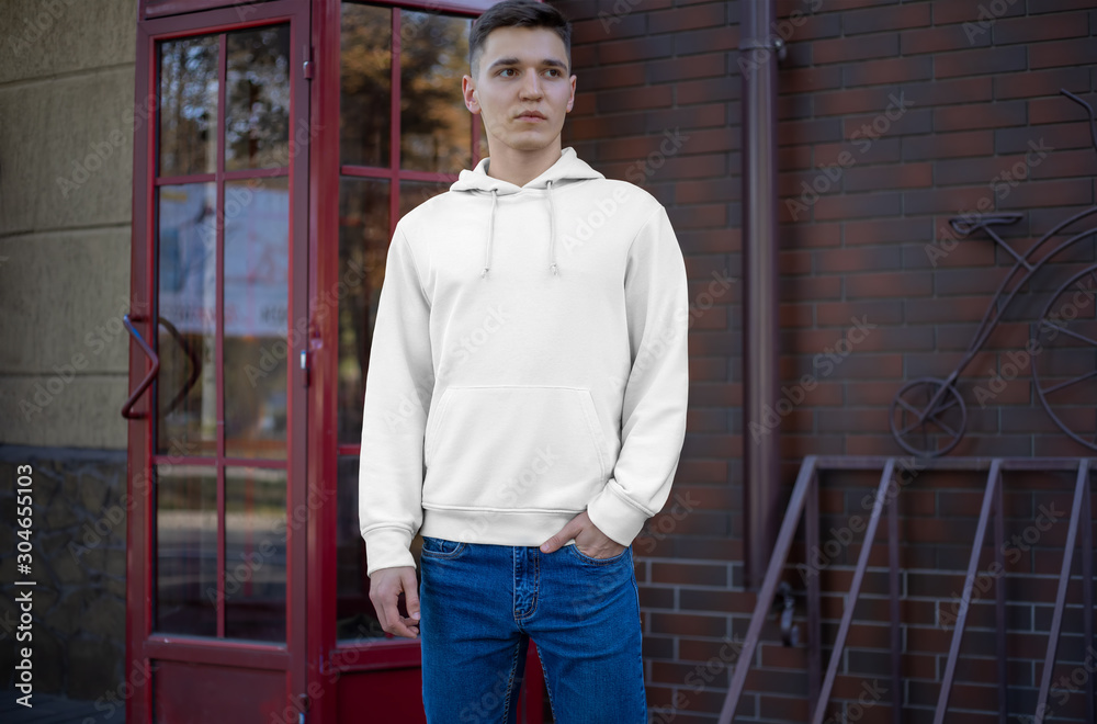 Fototapeta premium Presentation of a white hoodie on a young guy on the street, front view.
