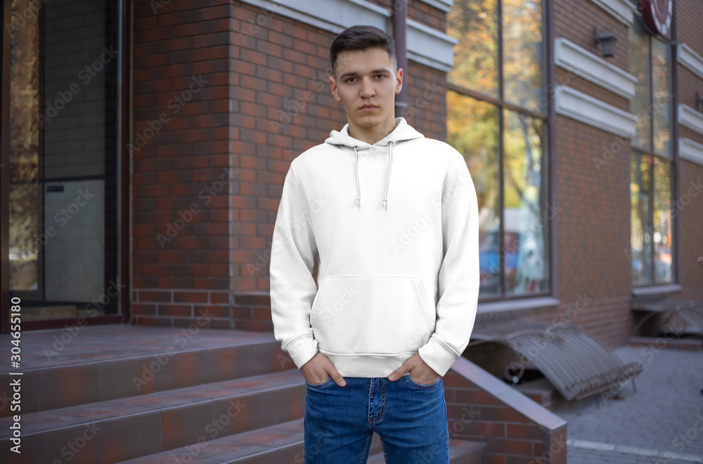 Fototapeta premium Template male white hoodie on a guy, front view, presentation of clothes on the street.