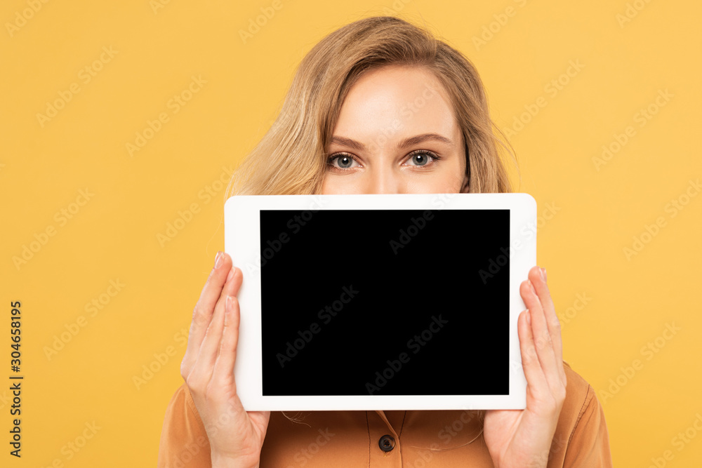 Blonde woman covering face with digital tablet with blank screen isolated on yellow Blonde woman covering face with digital tablet with blank screen isolated on yellow