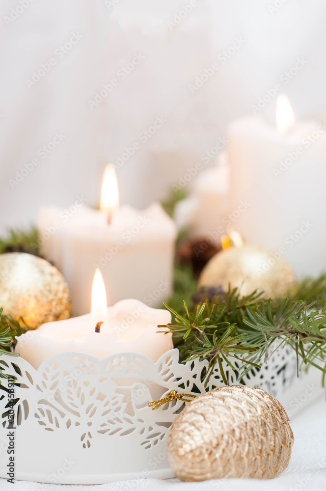 Christmas or New Year card. White burning candles on a light background. Golden balls and boxes with gifts.