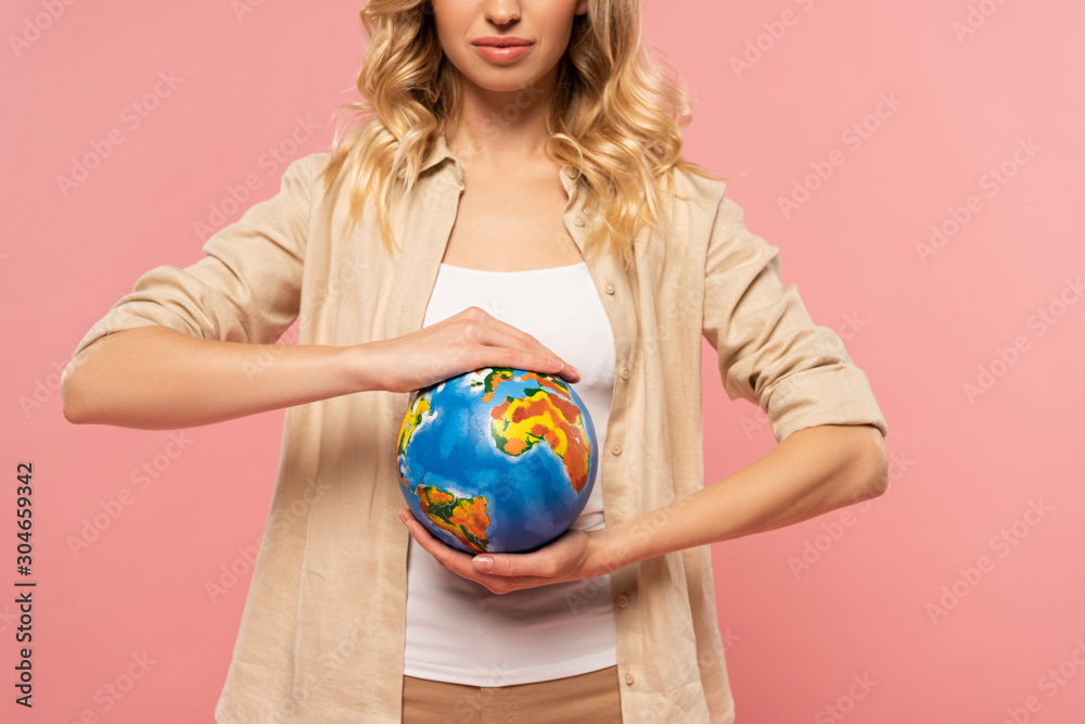 Cropped view of blonde woman holding globe isolated on pink Cropped view of blonde woman holding globe isolated on pink