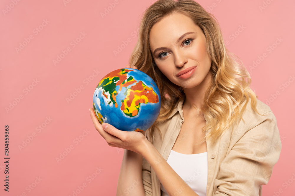 Smiling blonde woman holding globe isolated on pink Smiling blonde woman holding globe isolated on pink