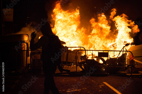 Manifestante camina delante de un contenedor quemado. photo