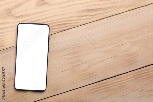 Smart phone on wooden table background with copy space. Flat lay, top view