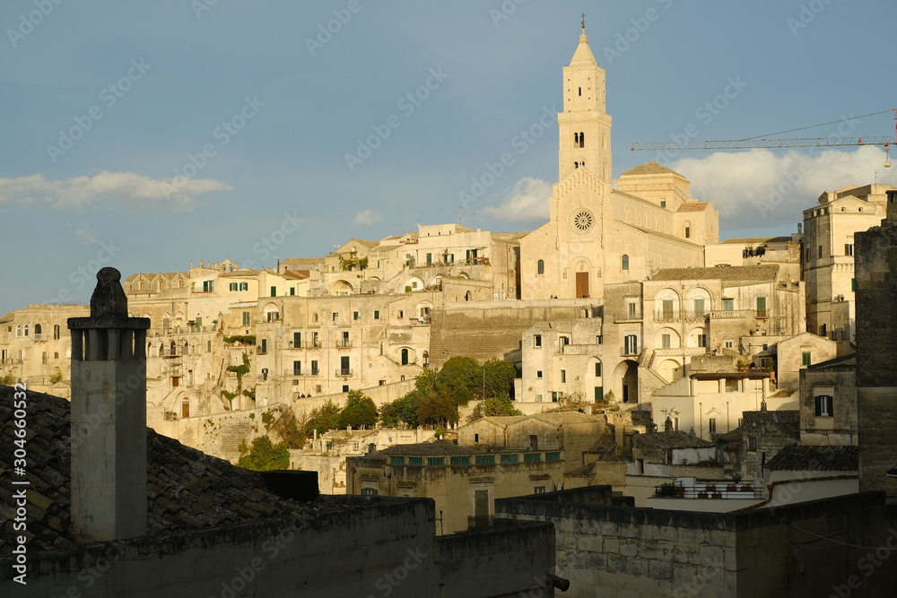 Cathedral Church of the Madonna della Bruna and of Sant'Eustachio in Matera. House with funnel in the foreground. Morning light..