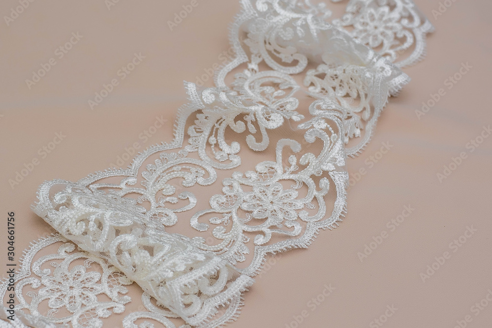 Texture lace fabric. lace on white background studio. thin fabric made of yarn or thread. a background image of ivory-colored lace cloth. White lace on beige background. Texture lace fabric. lace on white background studio. thin fabric made of yarn or thread. a background image of ivory-colored lace cloth. White lace on beige background.