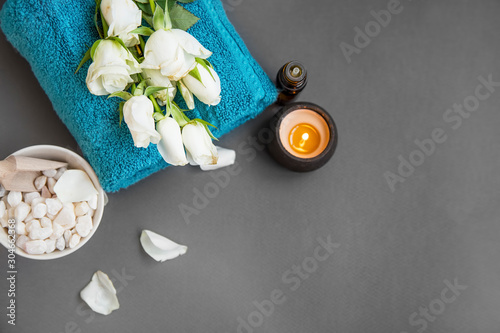 Spa still life with towels, white flowers, candle and essential oil, top view of spa setting with copy space