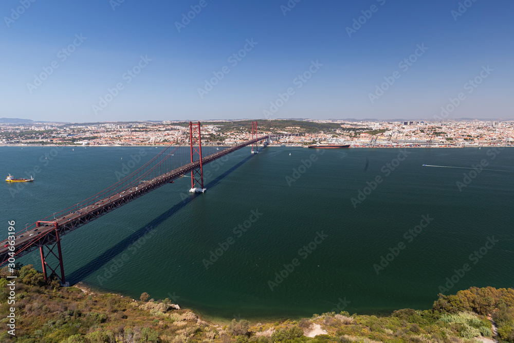 Lisbon, 25 de Abril Bridge (Ponte 25 de Abril, 25th of April Bridge) and Tagus River in Portugal viewed from above on a sunny day in the summer.