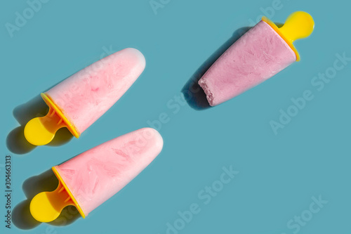 Homemade pink ice cream on a blue background. Natural fruit and berry popsicle  without sugar on a hot summer day. Flat lay, top view, copy space for text
