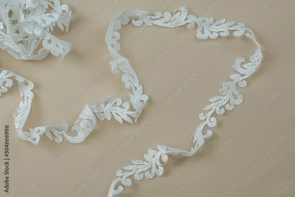 Texture lace fabric. lace on white background studio. thin fabric made of yarn or thread. a background image of ivory-colored lace cloth. White lace on beige background. Texture lace fabric. lace on white background studio. thin fabric made of yarn or thread. a background image of ivory-colored lace cloth. White lace on beige background.