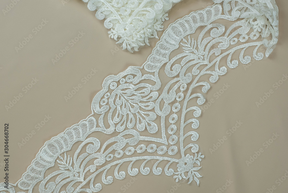 Obraz premium Texture lace fabric. lace on white background studio. thin fabric made of yarn or thread. a background image of ivory-colored lace cloth. White lace on beige background.
