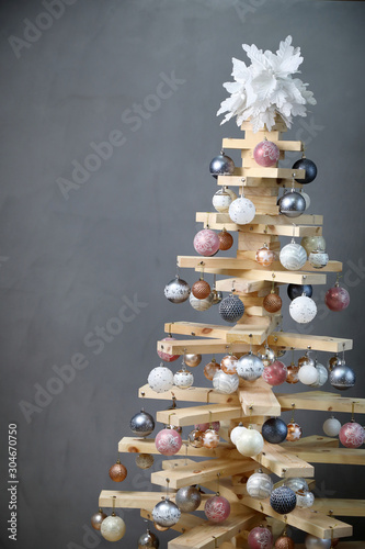 Alternative Christmas tree . the original Christmas tree in the new year of wood boards, decorated with balls, on a gray background . vertically, copy space .