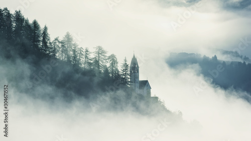 Mystical foggy scenery of church in Dolomites mountains