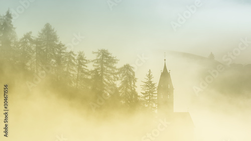Mystical foggy scenery of church in Dolomites mountains